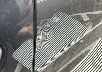 View of a dent in a BMW with a stiped reflection